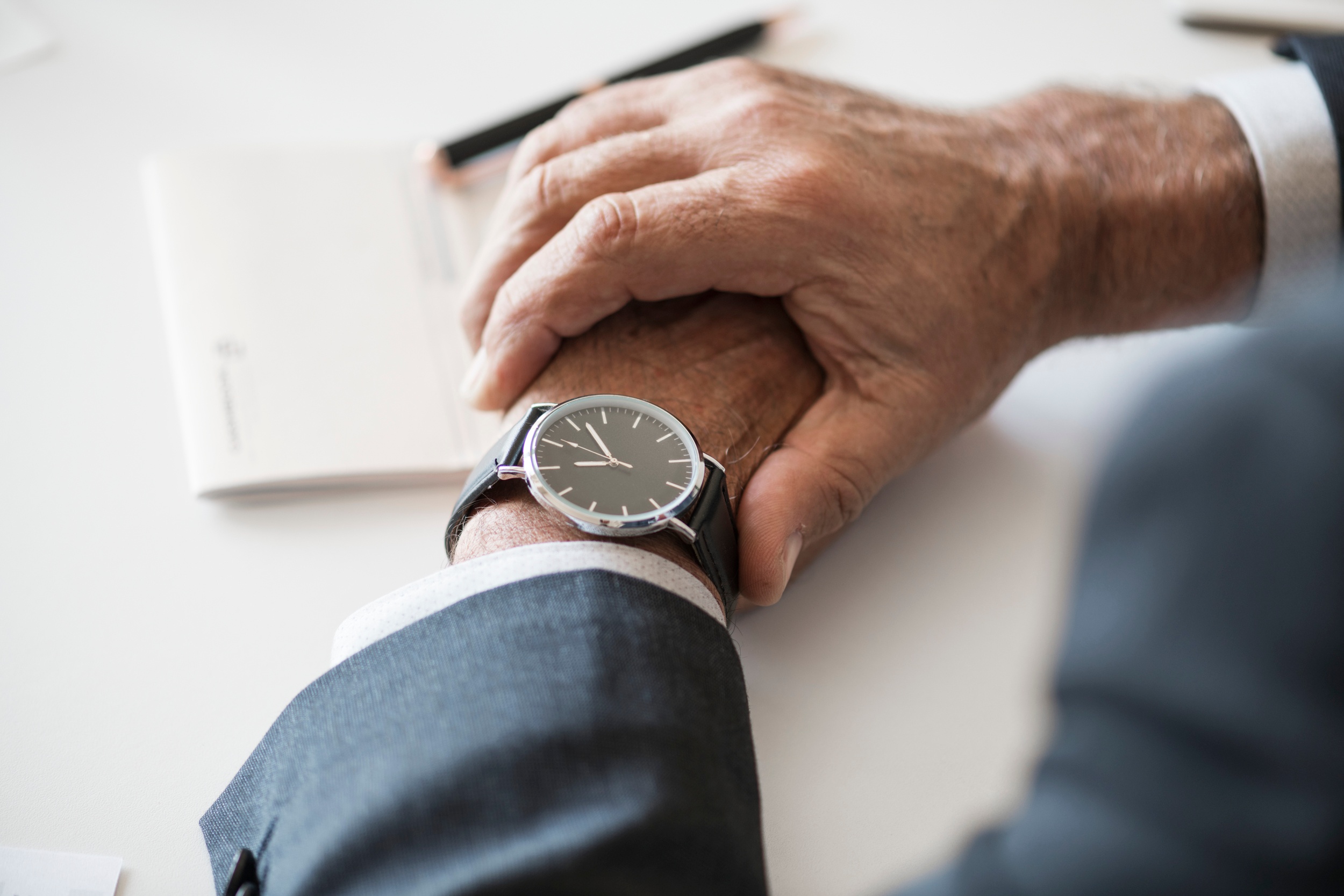 An image focused on a wristwatch, on the wrist of a person wearing a business suit. Image source: https://stocksnap.io/photo/VL9LPY5XWL